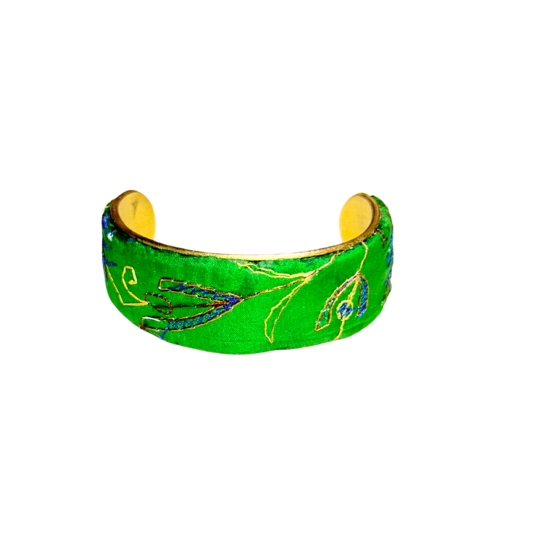 A handmade brass cuff bracelet from Redd Dott Jewelry, crafted and stamped in Shreveport, LA. Wrapped in green silk with gold and blue embroidered vines, this nature inspired jewelry piece features a botanical motif over a vintage brass base.







