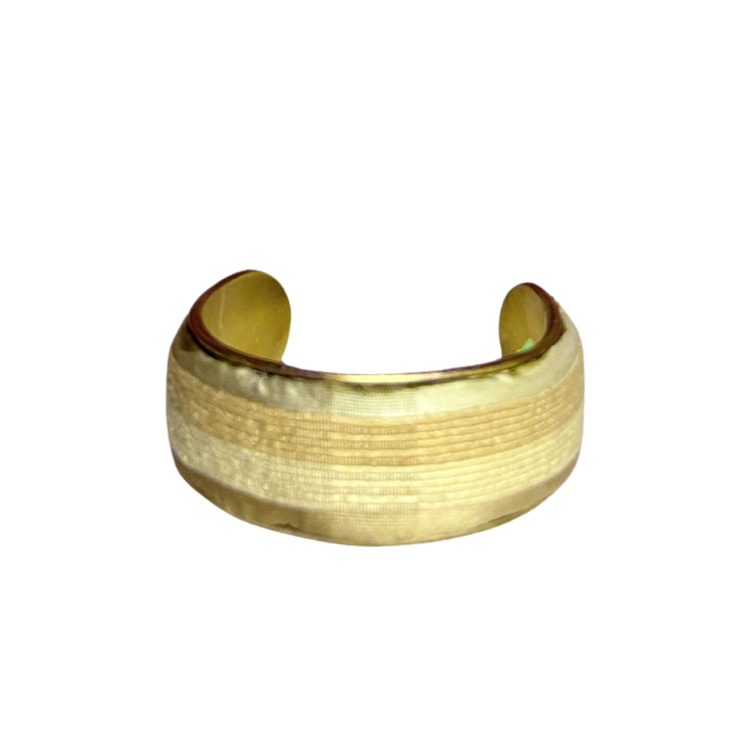 The Emery brass cuff bracelet features a sleek, textured golden fabric overlay on a polished vintage brass base. This minimalist power bracelet radiates quiet strength and timeless style.