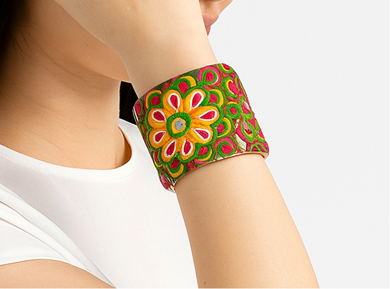 Woman wearing the Aurora Brass Cuff Bracelet with bright embroidered florals in pink, orange, and yellow on a polished brass base — handcrafted in Shreveport, LA by Redd Dott Jewelry.