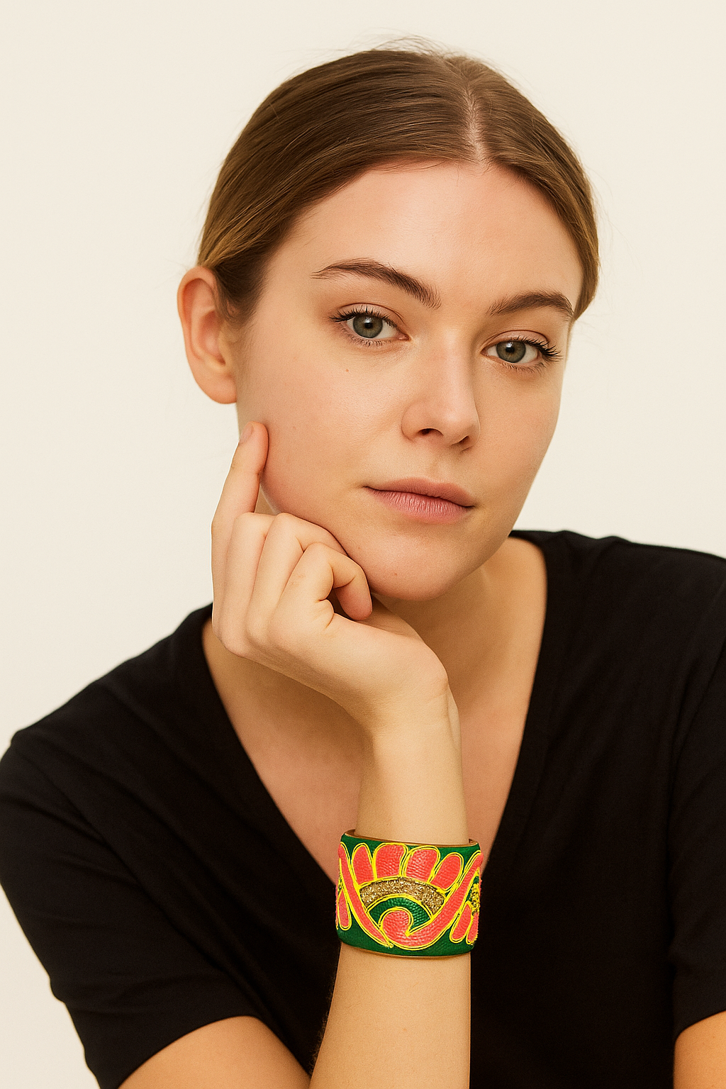 A female model wearing a one of a kind jewelry brass cuff bracelet for women—a 2-inch wide, open-back design wrapped in emerald-green fabric embroidered with coral and yellow floral swirls, showcased on her wrist.