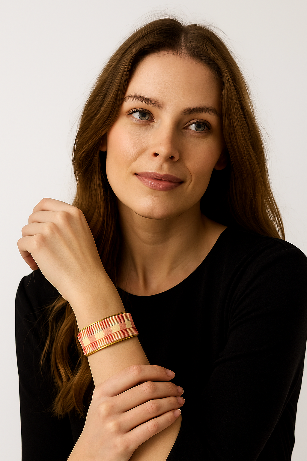Close-up portrait of a female model wearing a 1-inch wide yellow-and-red gingham fabric–wrapped brass cuff bracelet; the open-back ends peek out as she rests her hand against her chin.