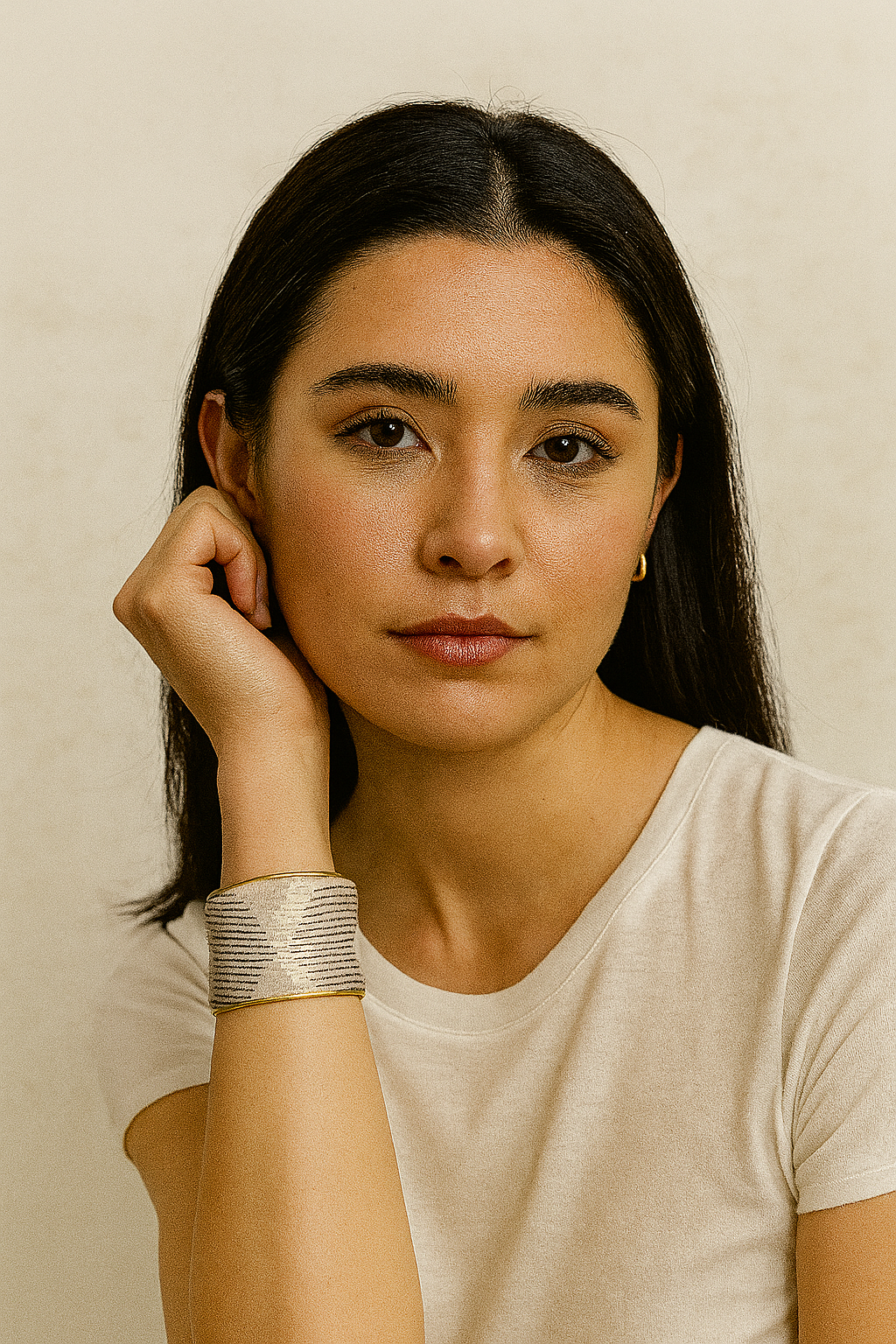 A woman wearing the Inaya cuff bracelet on her wrist, paired with a neutral top. The brass cuff’s subtle shimmer and chevron pattern add elegance and refinement to her understated look.